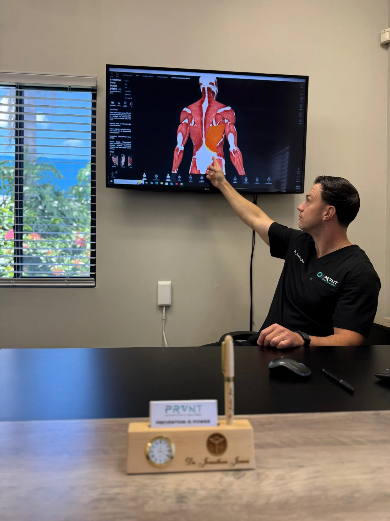 PRVNT clinician explaining anatomy on a wall-mounted display.